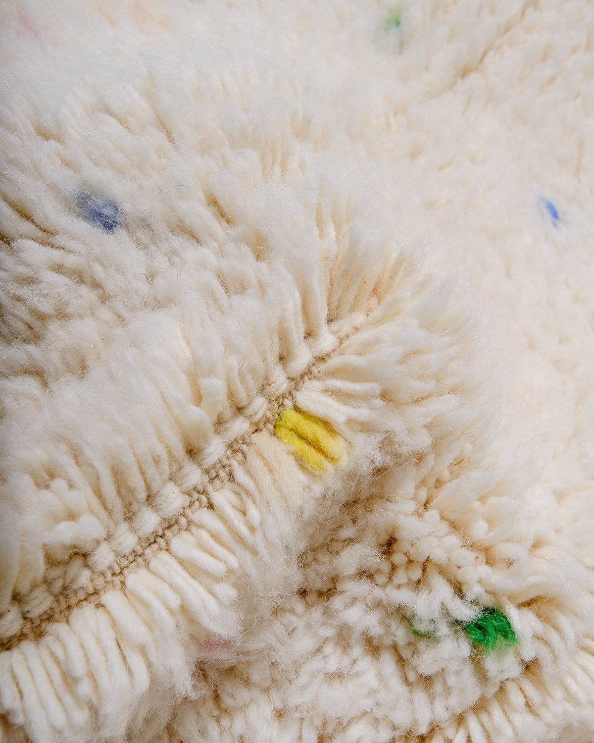 Detail of cream wool rug showing the density of the wool and coloured strands that make up the polka dots.
